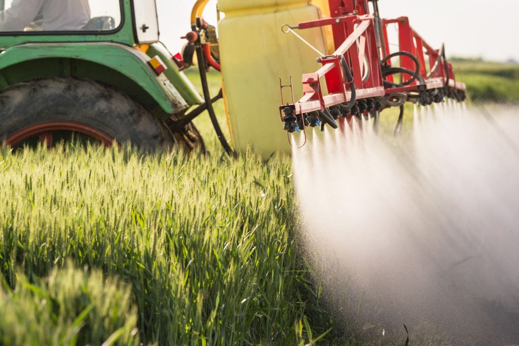 tractor spraying glyphosate on field crop