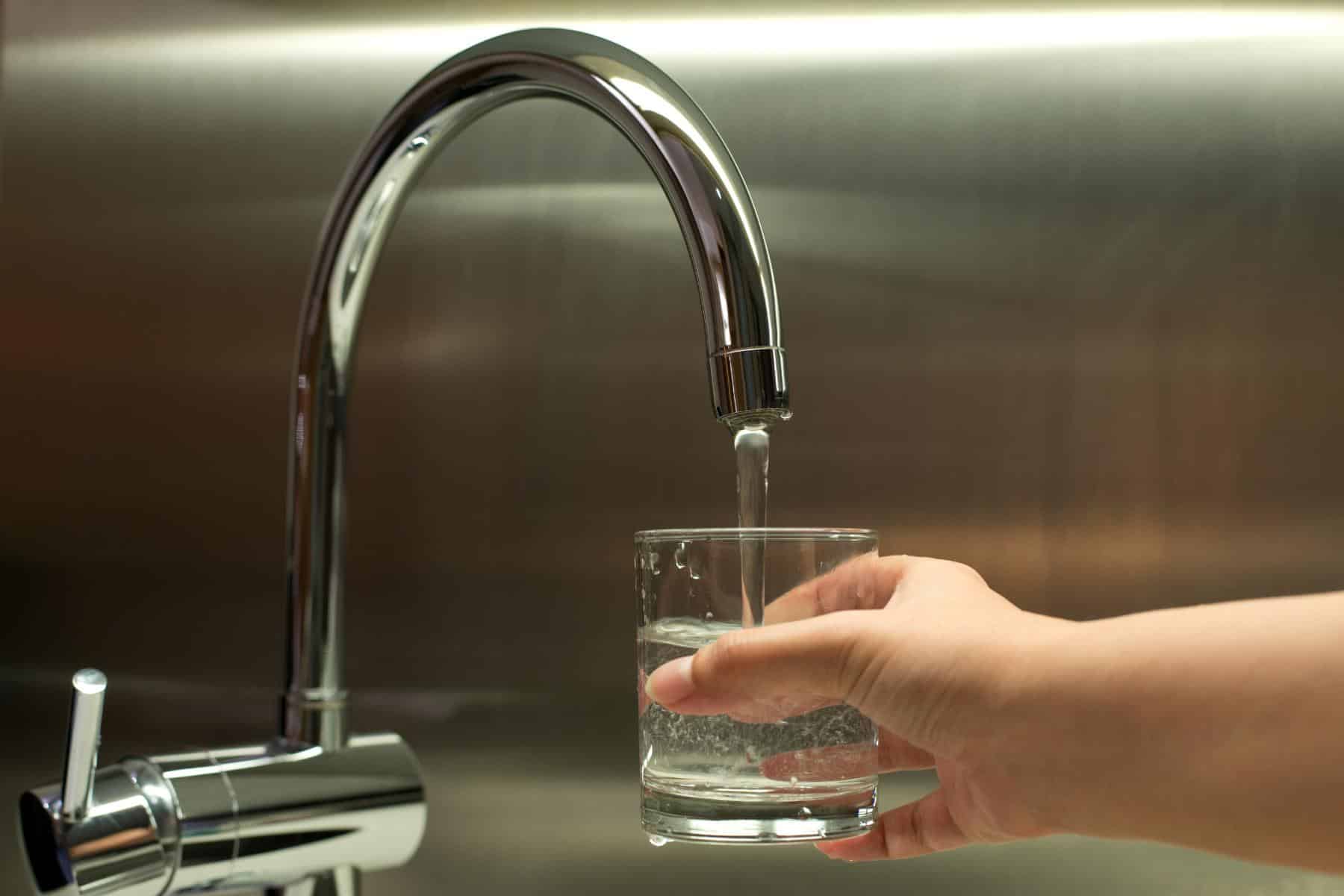 A person getting a glass of water from a water faucet.