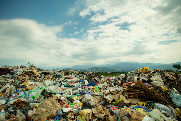 Garbage landfilll in theforeground with blue sky and mountains in the background.