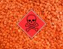 Background of red lentils with a red square with the toxic skull and crossbones symbol inside.